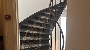 Eine Treppe mit Teppichmuster und einer Holzhandläufe.