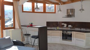 A modern kitchen with a built-in oven, a bar area, and a view of the city through large windows. - Hotel Petr (Karlovy Vary)