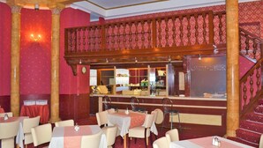 A dining area with tables and chairs, a bar area with a counter and stools, and a staircase leading to an upper level. - Hotel Petr (Karlovy Vary)