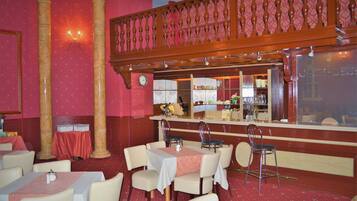 Un ristorante con zona bar, tavoli, sedie e un pavimento ricoperto di tappeto rosso.