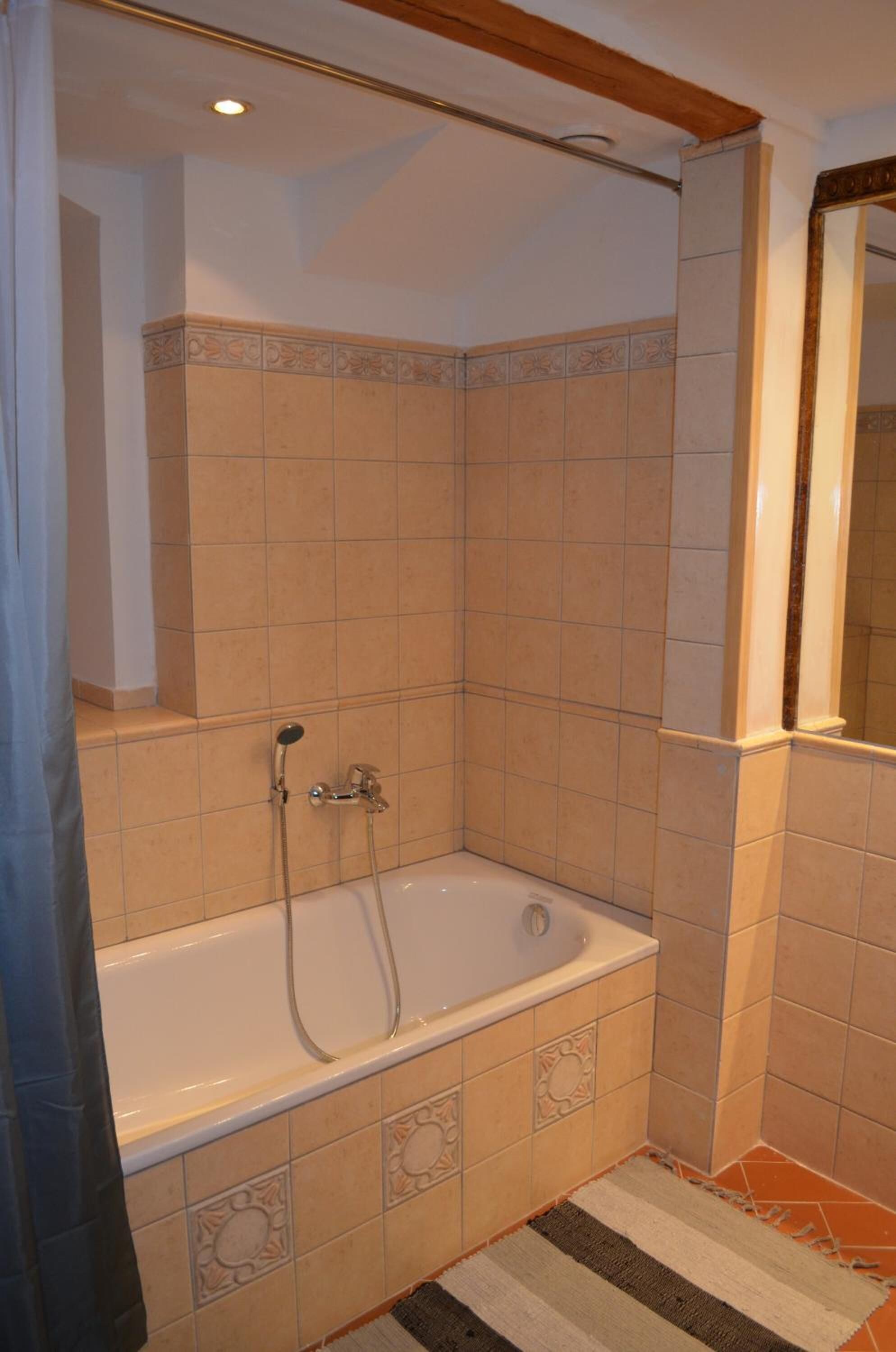 A bathroom with a bathtub, shower, and tiled walls.