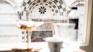 Vista de un edificio de piedra con un ventanal decorativo y una mesa con una taza y un platito.