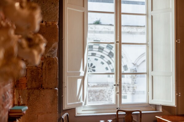 A room with a large window, stone walls, and a view of a clock tower.