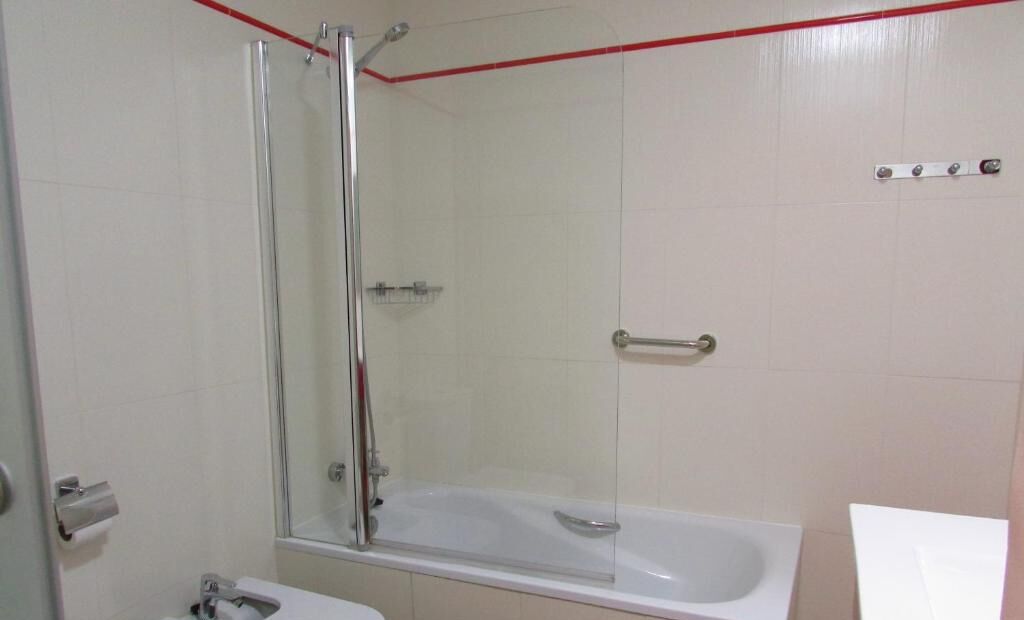 A bathroom with a glass-enclosed shower, a white bathtub, and a toilet.