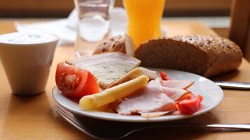 A breakfast plate with bread, cheese, ham, and tomato slices.