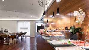 Una cocina moderna con armarios de madera, una encimera larga con productos alimenticios e iluminación colgante.