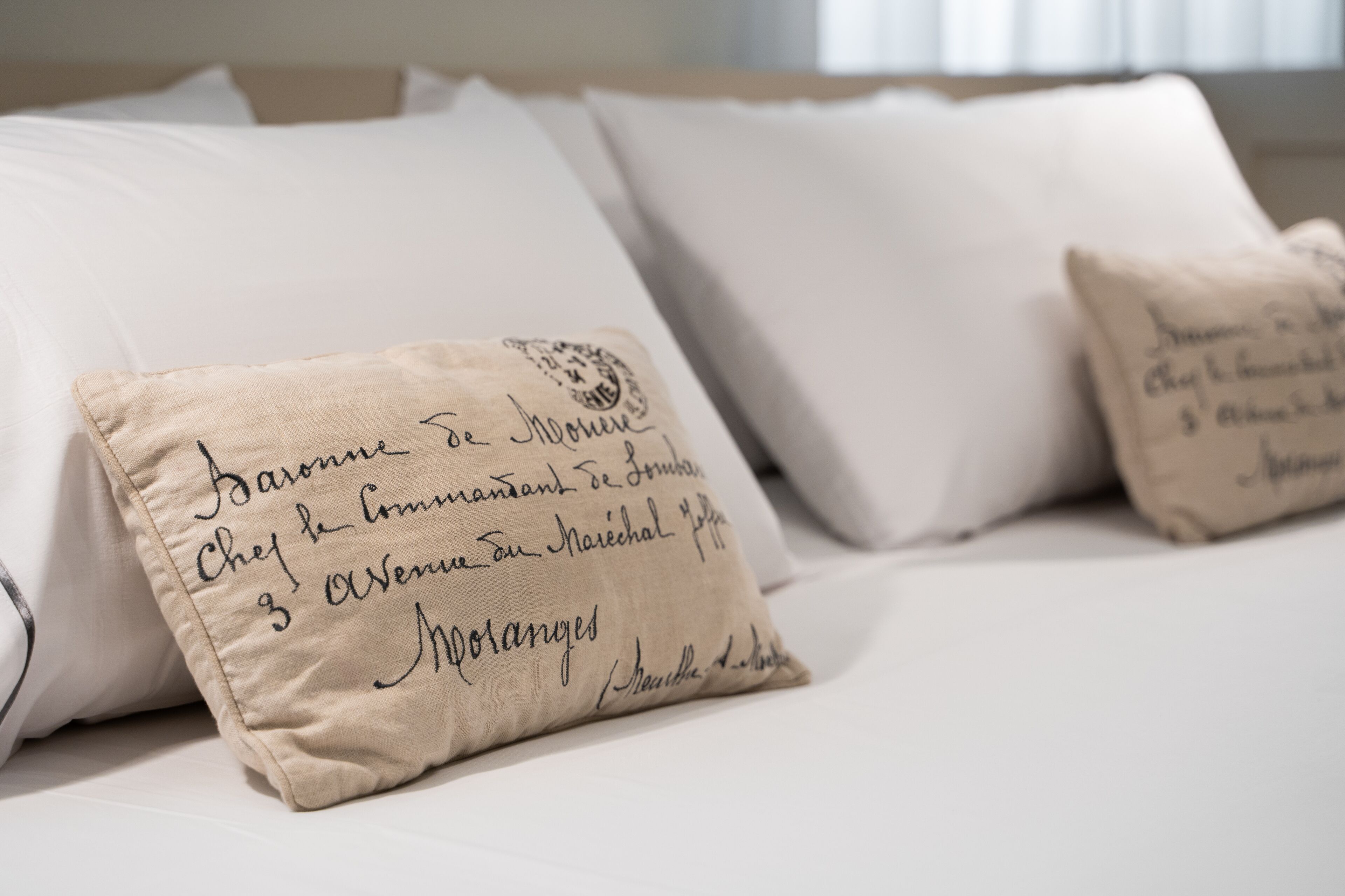 A bed with white linens and pillows with handwritten messages.