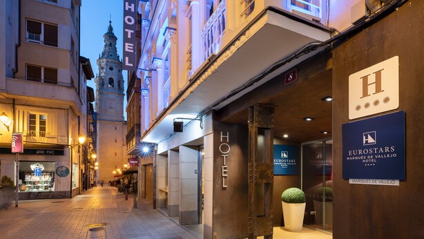 Un hotel con un cartel prominente que dice 'HOTEL', una torre del reloj al fondo y un cartel de 'EUROSTARS' que indica la cadena hotelera.