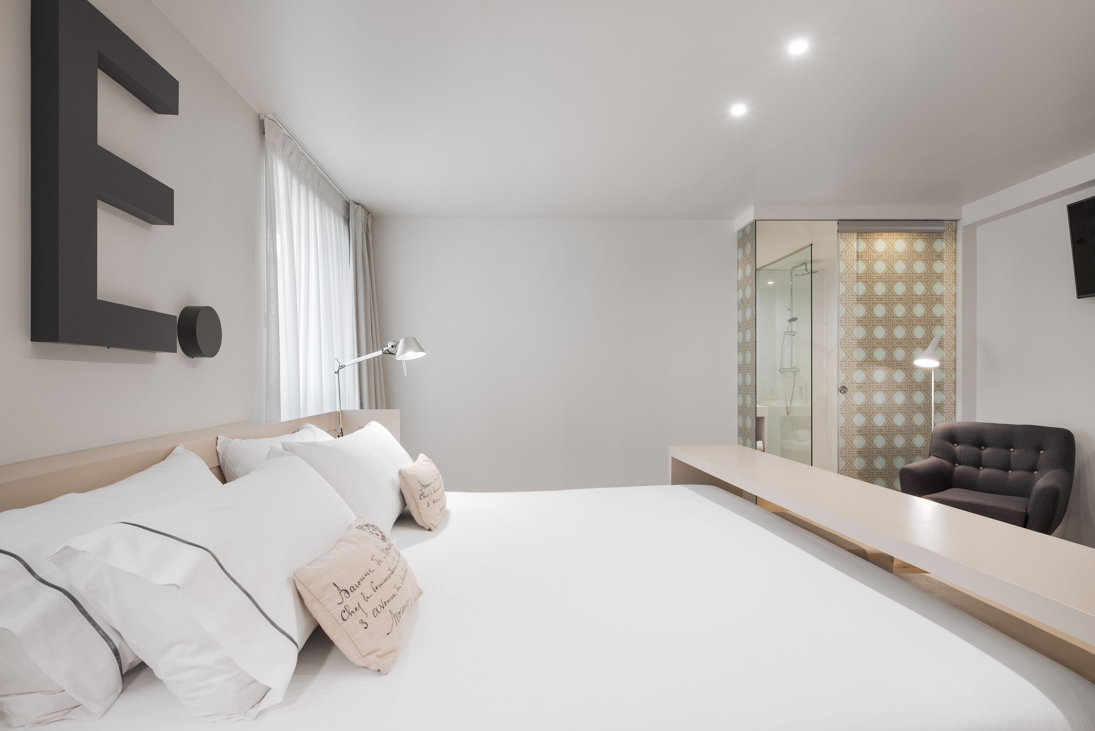Un dormitorio moderno con una cama grande, una mesita de noche, una silla y un espejo.