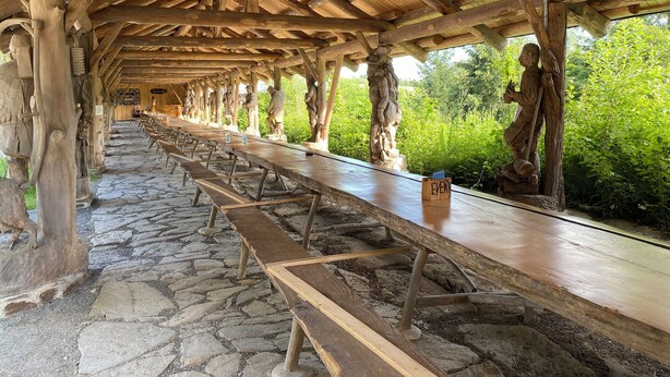Un espacio al aire libre cubierto con piso de piedra y bancos de madera dispuestos en filas.