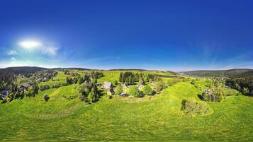 Panoramica di un paesaggio rurale con dolci colline, case sparse e fitti boschi.