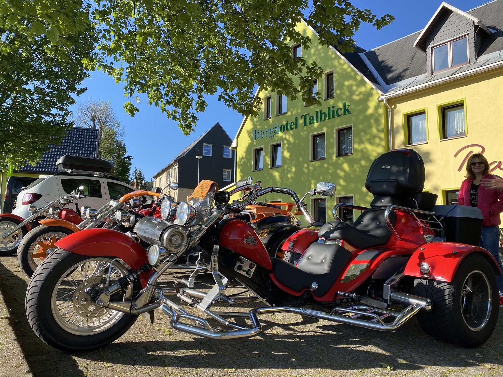 En motorcykel parkerad framför en byggnad med en skylt som visar texten ”Berghotel Talblick”.