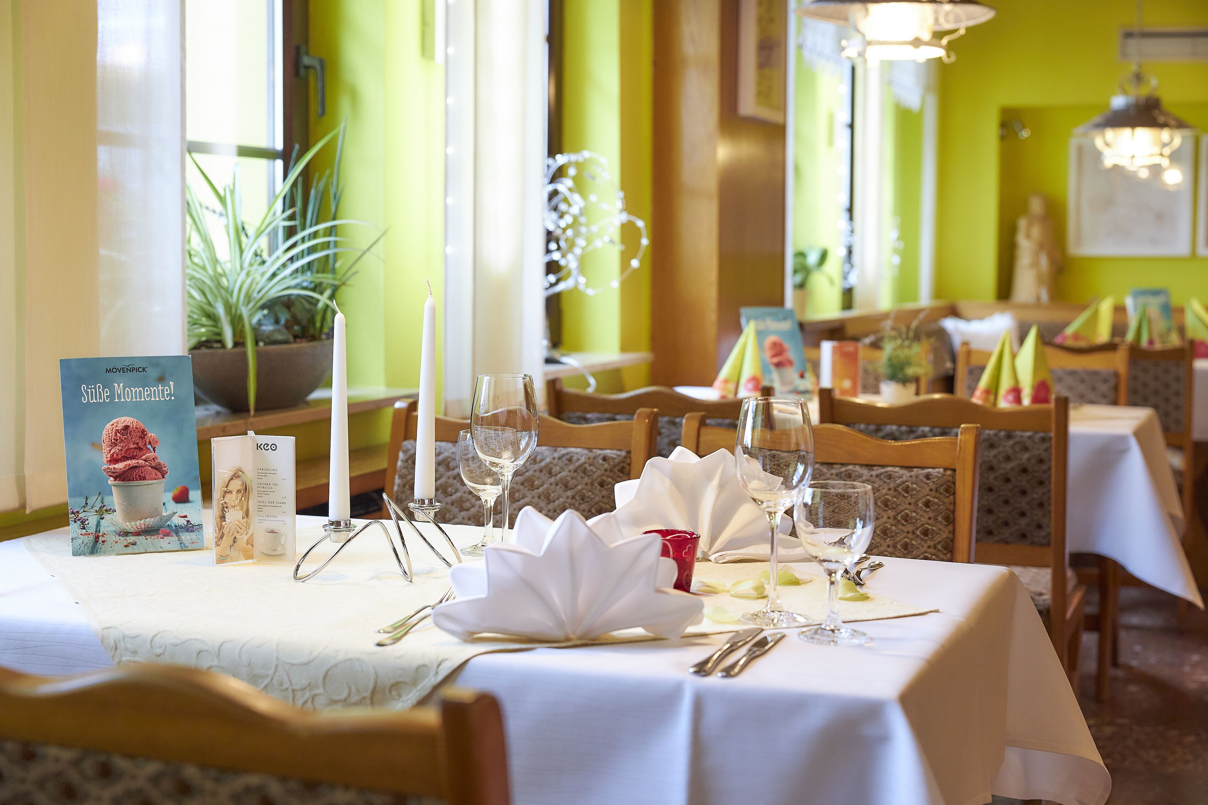 A restaurant table set with white tablecloth, candles, and a menu.