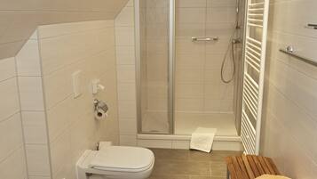 Ein modernes Badezimmer mit Dusche, Toilette und Sitzbank.
