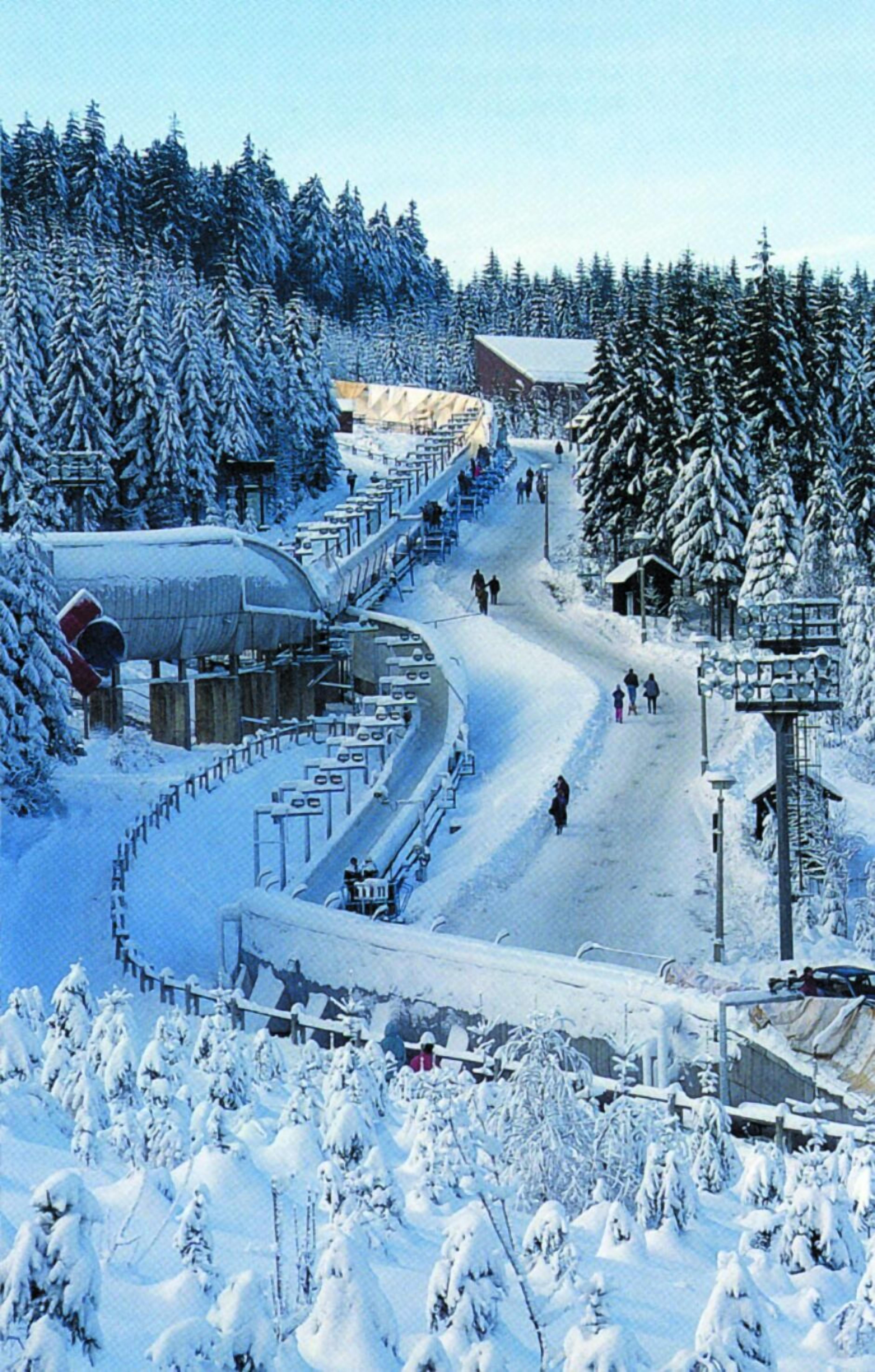 Un centro de esquí cubierto de nieve con un telesilla, pistas de esquí y árboles nevados.