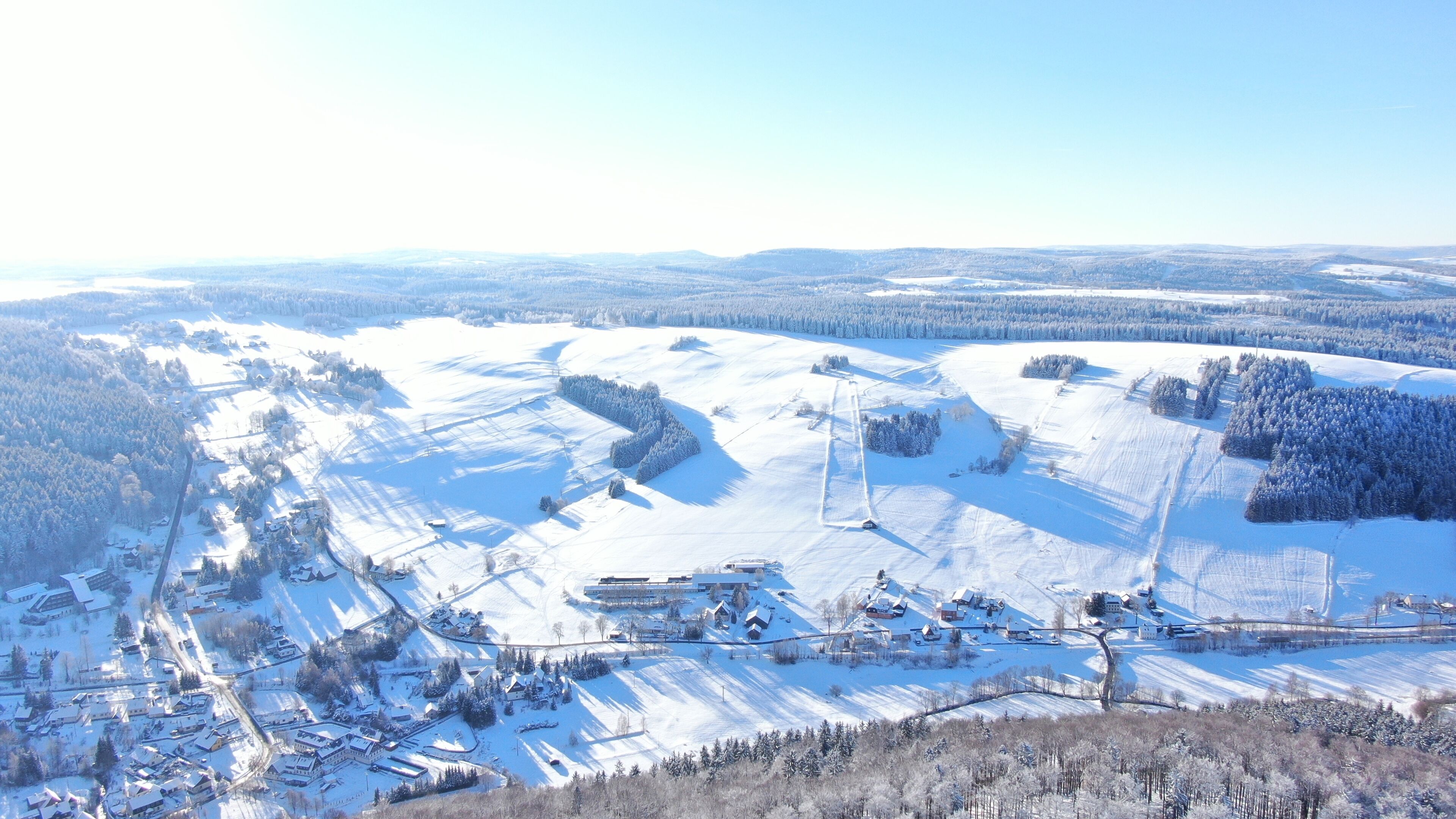 Schneebedeckte Landschaft mit einem Skigebiet, einschließlich Seilbahnen und Gebäuden.