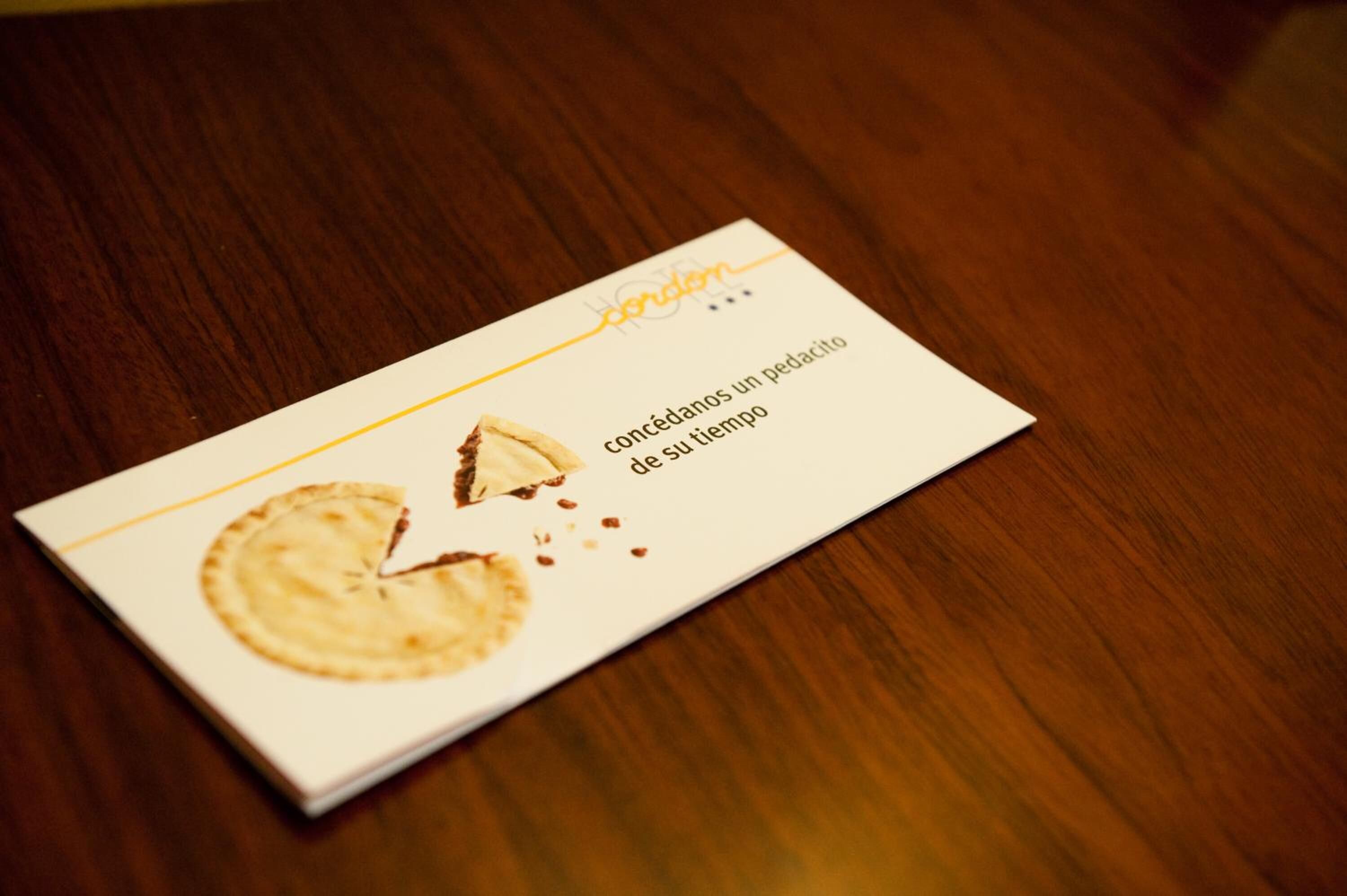 Tarjeta de presentación con logotipo y texto sobre una superficie de madera.