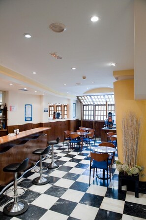 A restaurant with a checkered floor, bar area with stools, and tables with chairs.