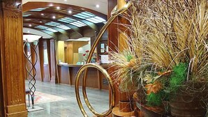 A lobby with a modern design, featuring a reception desk, a staircase, and a decorative plant arrangement. - Cordón (Burgos)