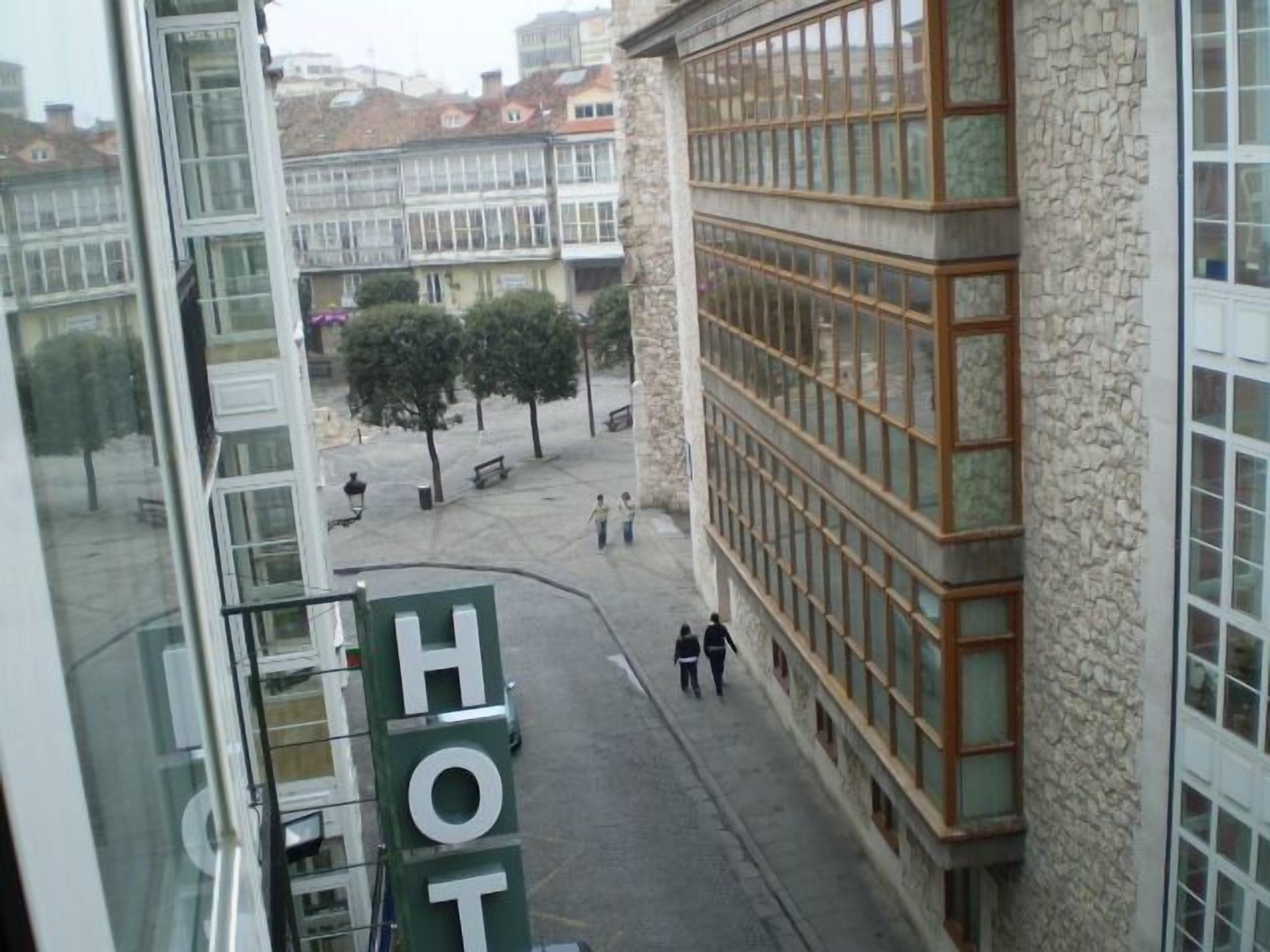 A hotel with a stone facade and large windows. There is a sign with the word "HOTEL" visible.