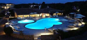 Una piscina al aire libre, sombrillas, sillones reclinables de piscina