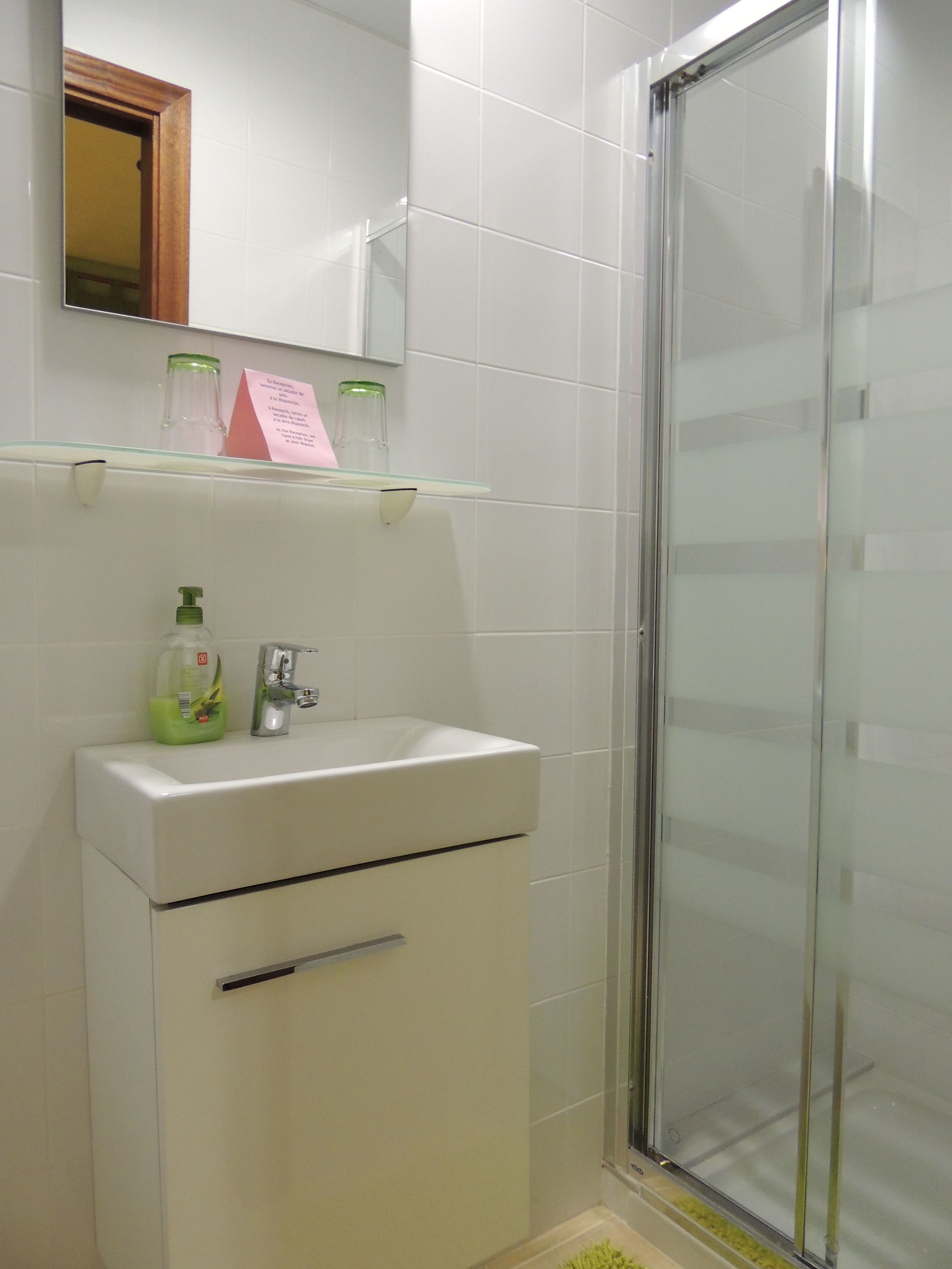A bathroom with a white sink, a glass shower enclosure, and a mirror above the sink.