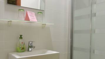 A bathroom with a white sink, a glass shower enclosure, and a mirror above the sink.