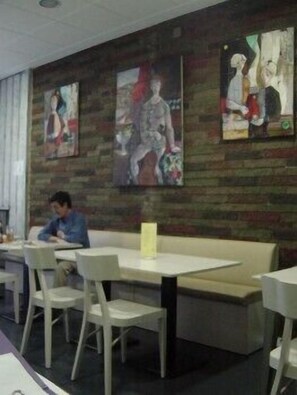 A restaurant interior with a brick wall, white tables, and chairs. - Can Massot (Angles)