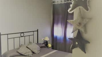 Un lit bien fait, avec des oreillers, une table de chevet avec une lampe et des décorations en forme d’étoiles sur le mur.