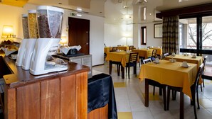 A hotel dining area with tables set for service, a coffee station, and a view of the outdoors.