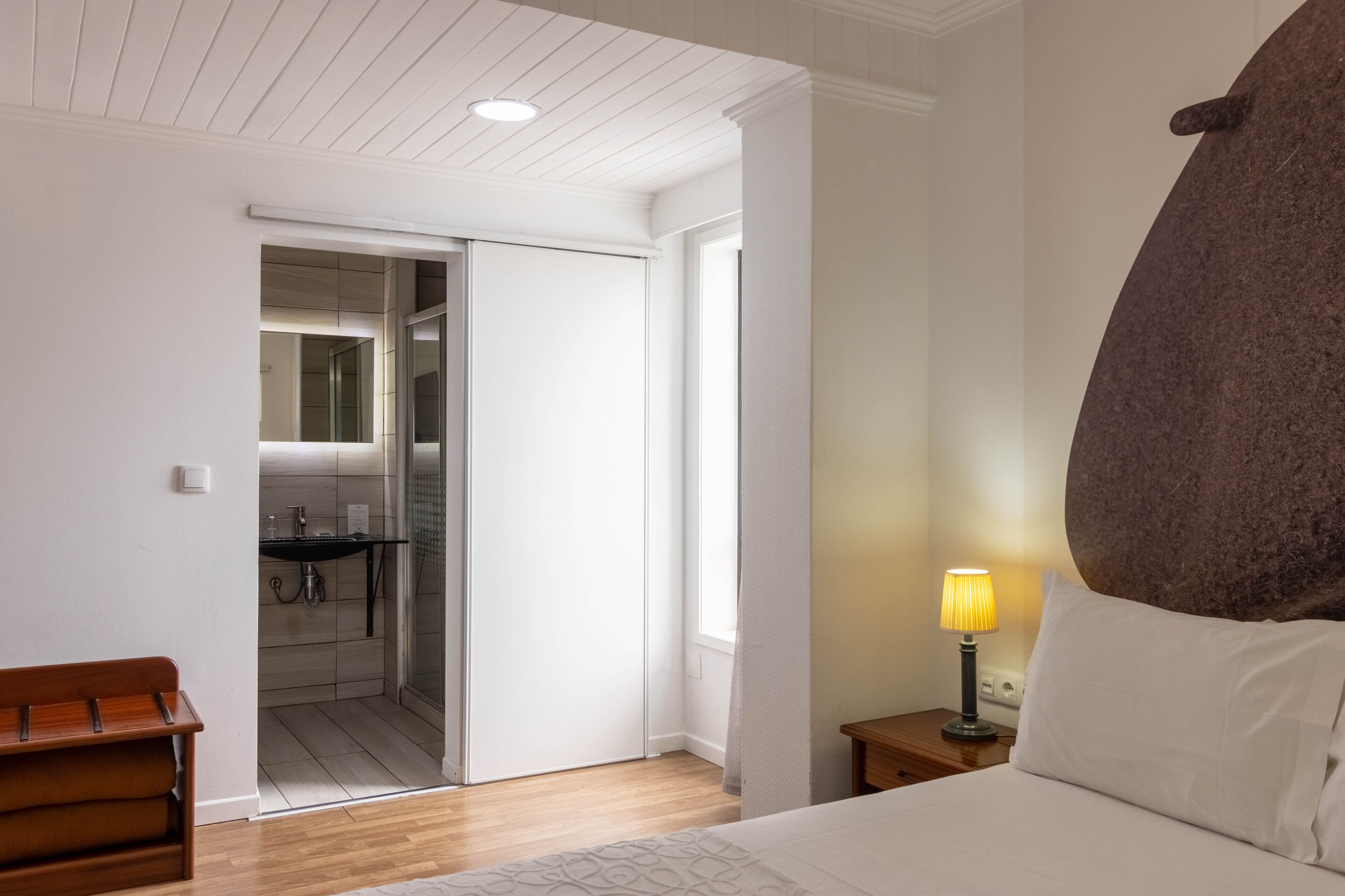 Une chambre à coucher avec un lit, une lampe de chevet et un grand mur en pierre servant d’élément décoratif.