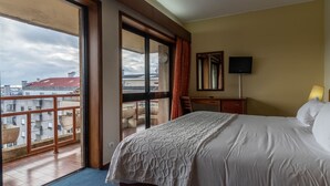 A hotel room with a large bed, a television, and a balcony with a view of the city. - AS São João da Madeira (Sao Joao da Madeira)