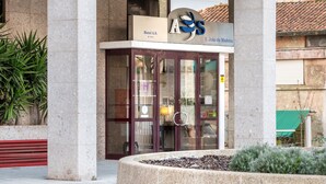 A hotel entrance with a glass door, a signboard, and a landscaped area with plants. - AS São João da Madeira (Sao Joao da Madeira)
