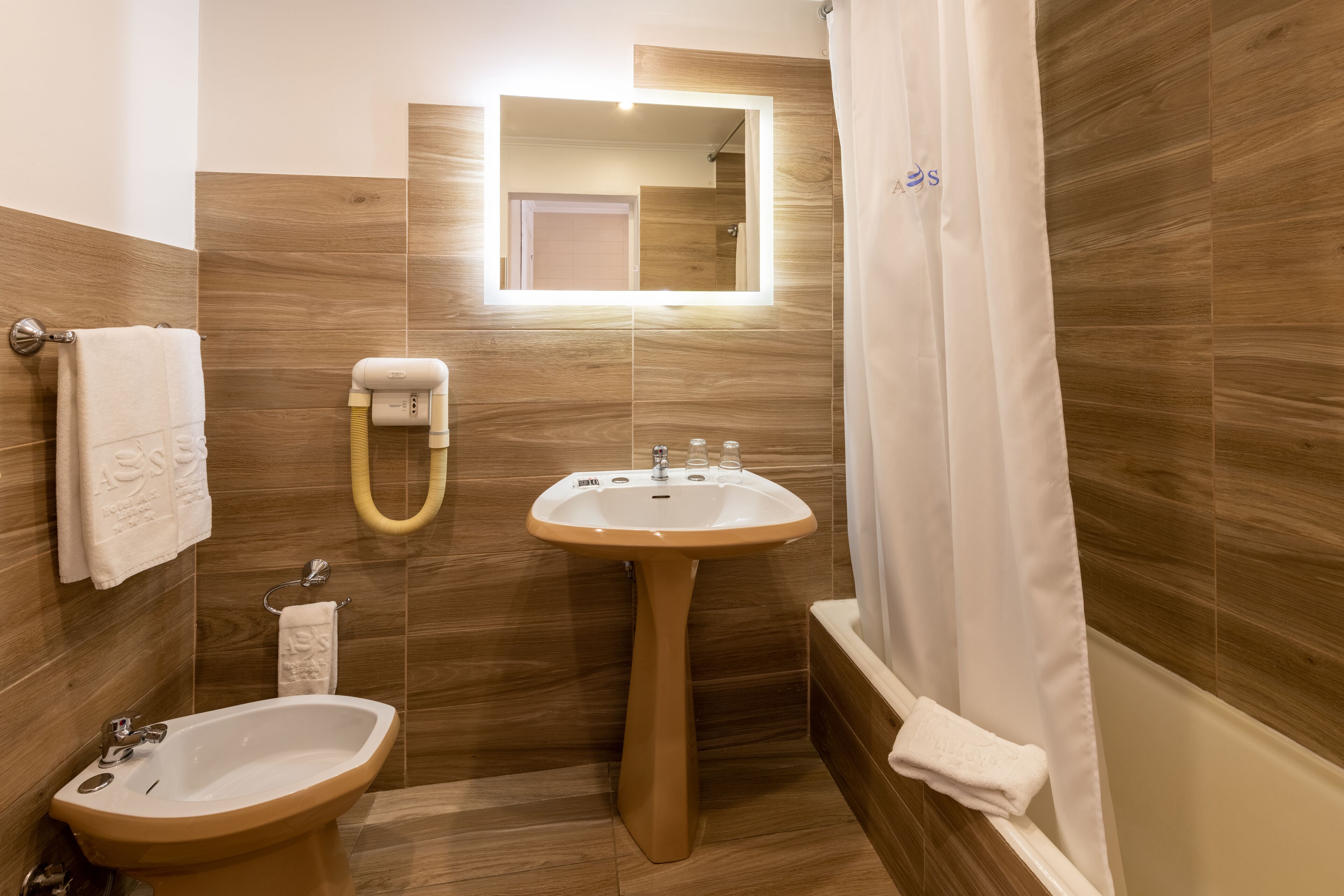 A bathroom with two sinks, a mirror, a towel rack, and a shower curtain.