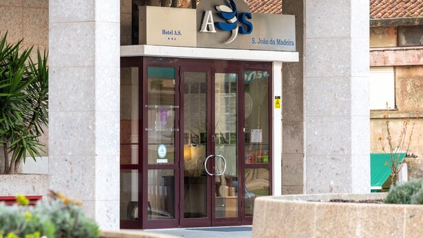 The entrance to Hotel A.S. S. João da Madeira with a glass door and a sign above.