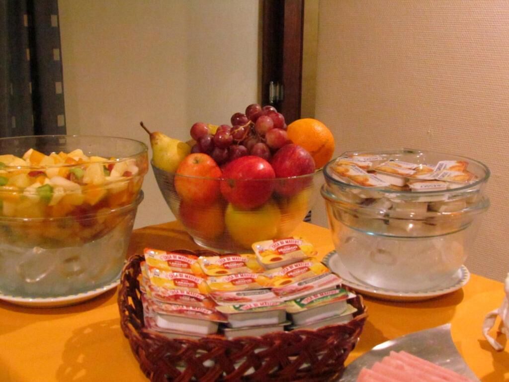 A buffet table with various food items including fruits, pastries, and packaged snacks.