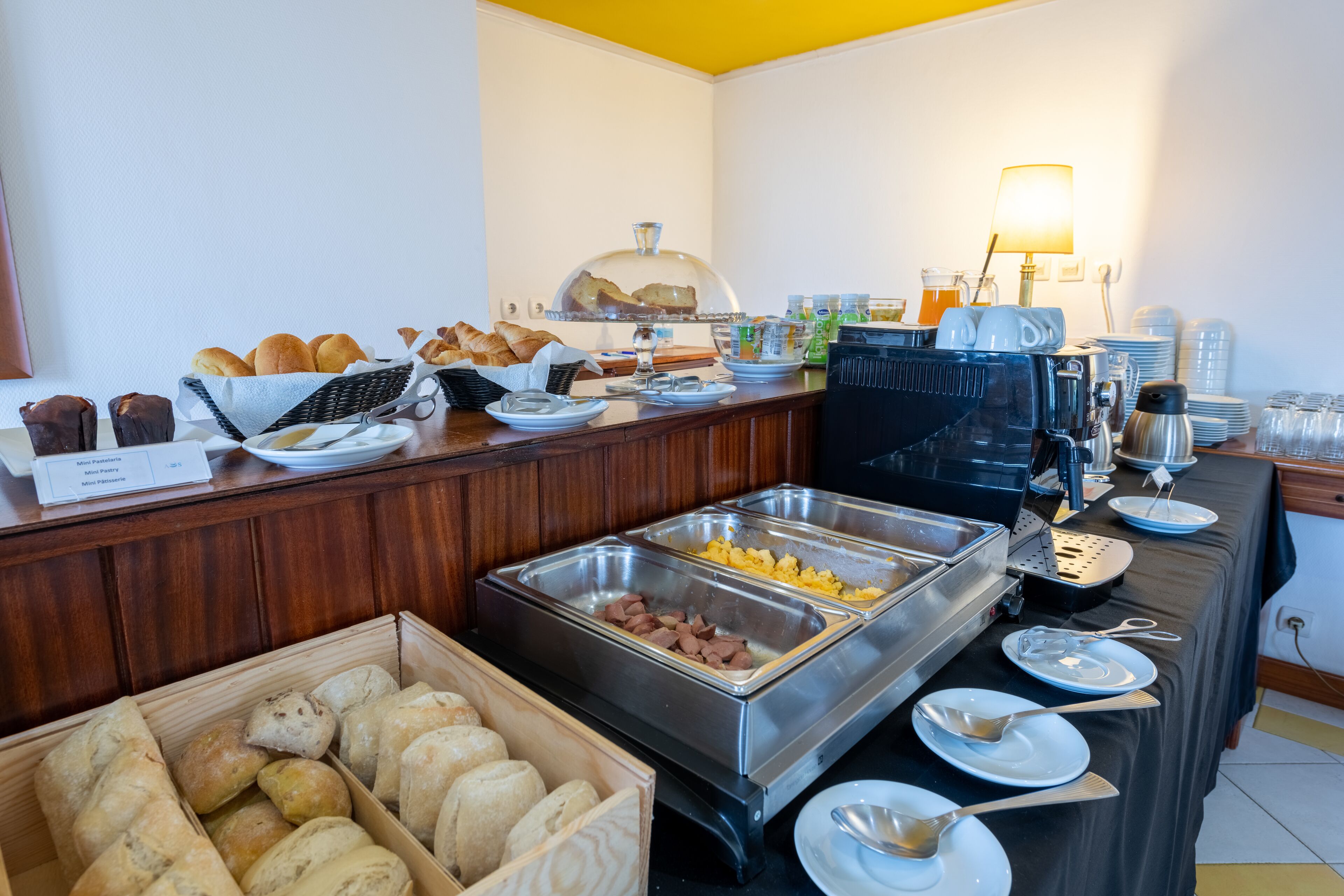 En buffé med ett varierat utbud av mat, inklusive bakverk och korv med bröd, samt en kaffestation.
