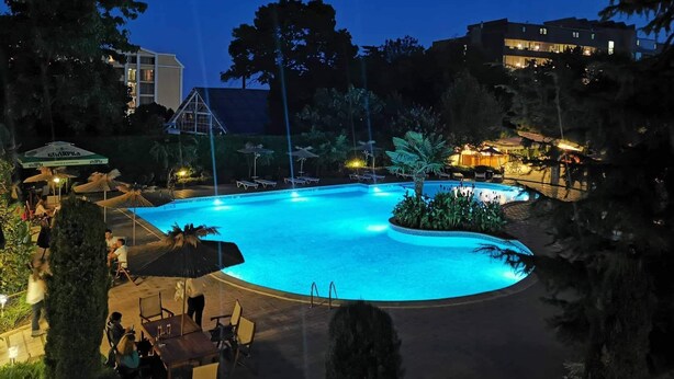 Une piscine entourée de chaises longues et de parasols, avec un bâtiment en arrière-plan.
