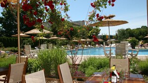 Un espace de restauration en plein air, avec des tables, des chaises et des parasols, donnant sur une piscine.