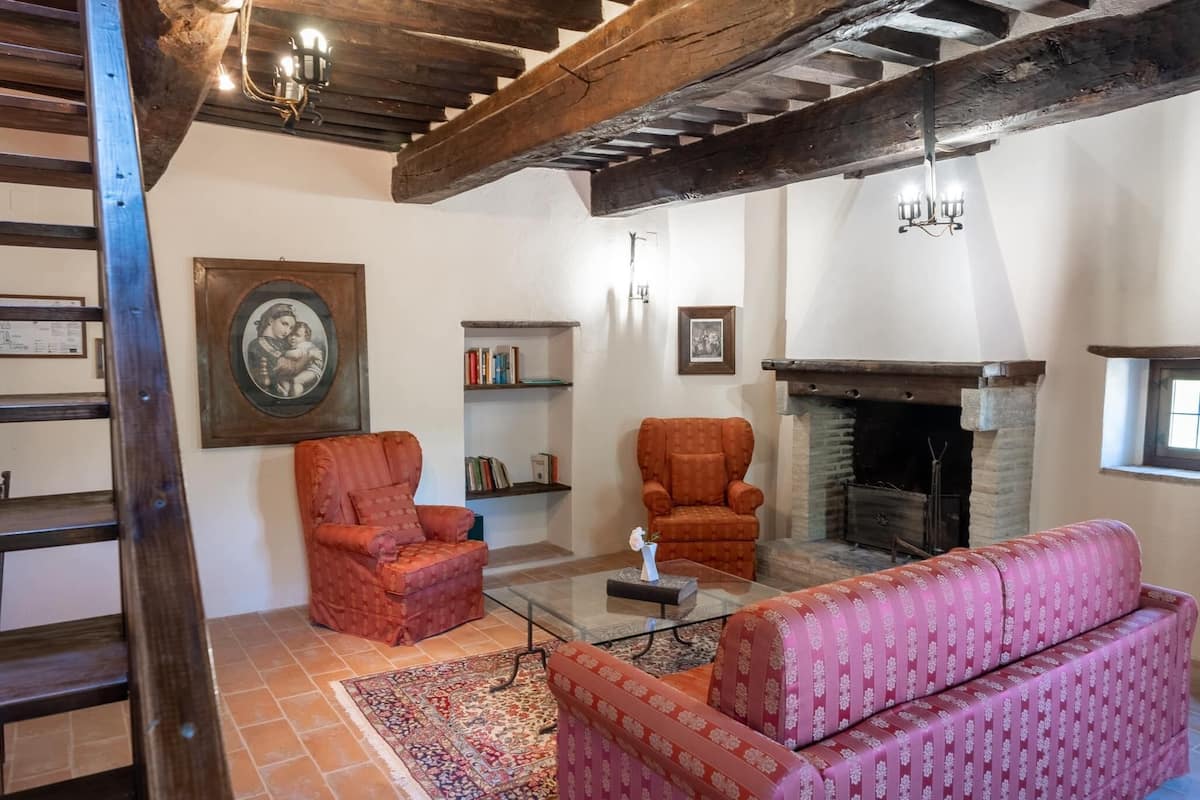 Una sala de estar tradicional con chimenea, vigas de madera y un sofá estampado.