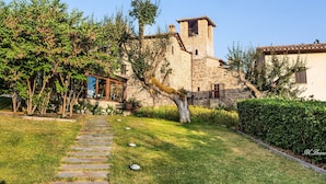 A stone building with a tower, surrounded by a well-maintained garden and a stone pathway.