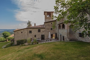 Un edificio de piedra con una torre de campanas, una escalera y un patio cubierto de césped.
