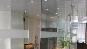 A modern conference room with glass walls, a glass table, and metal chairs.