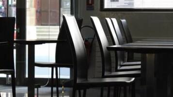 Un interior moderno con un separador de vidrio, una zona de comedor con sillas de metal y un ventanal grande.