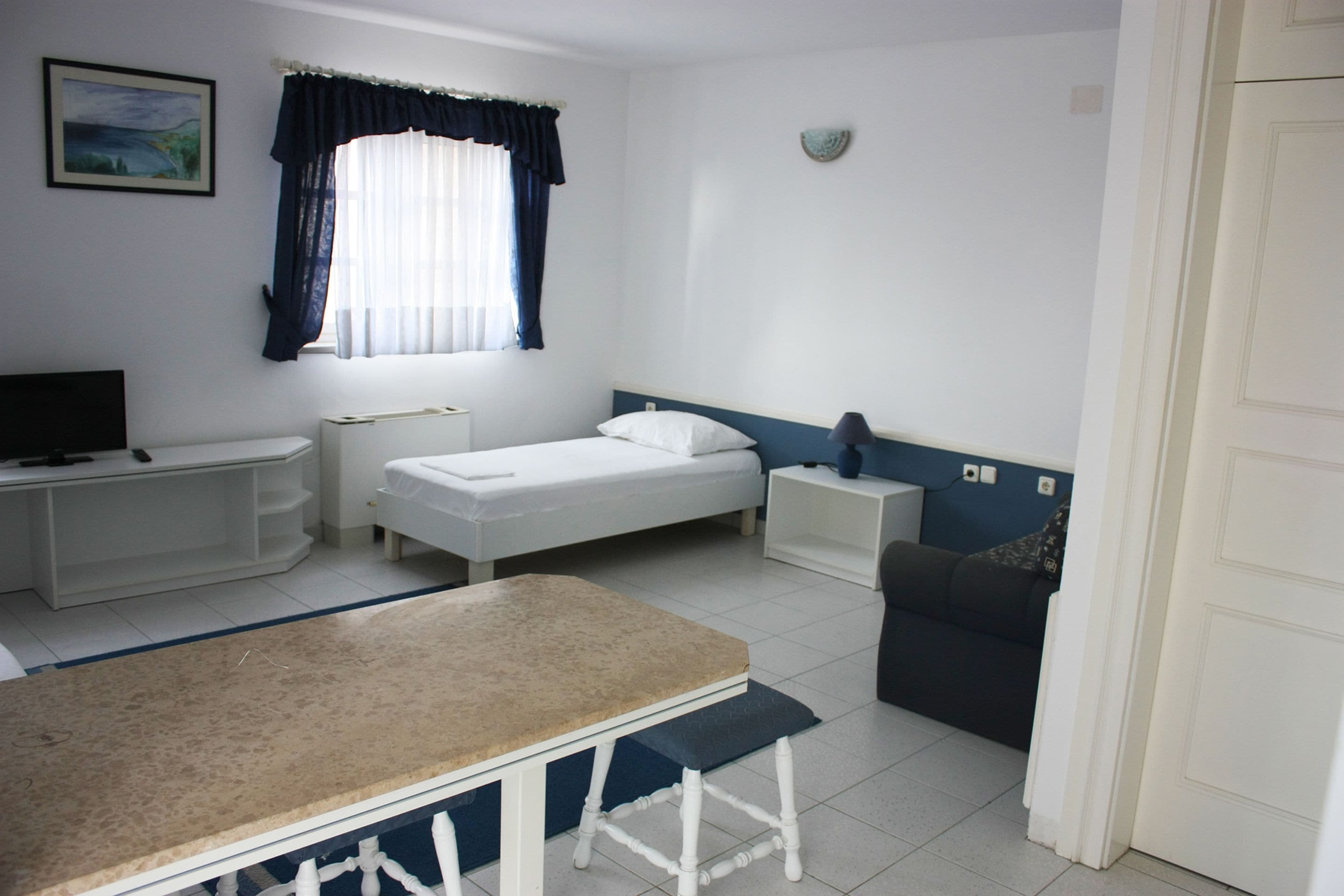 A small, clean room with a bed, a desk, a chair, and a table.