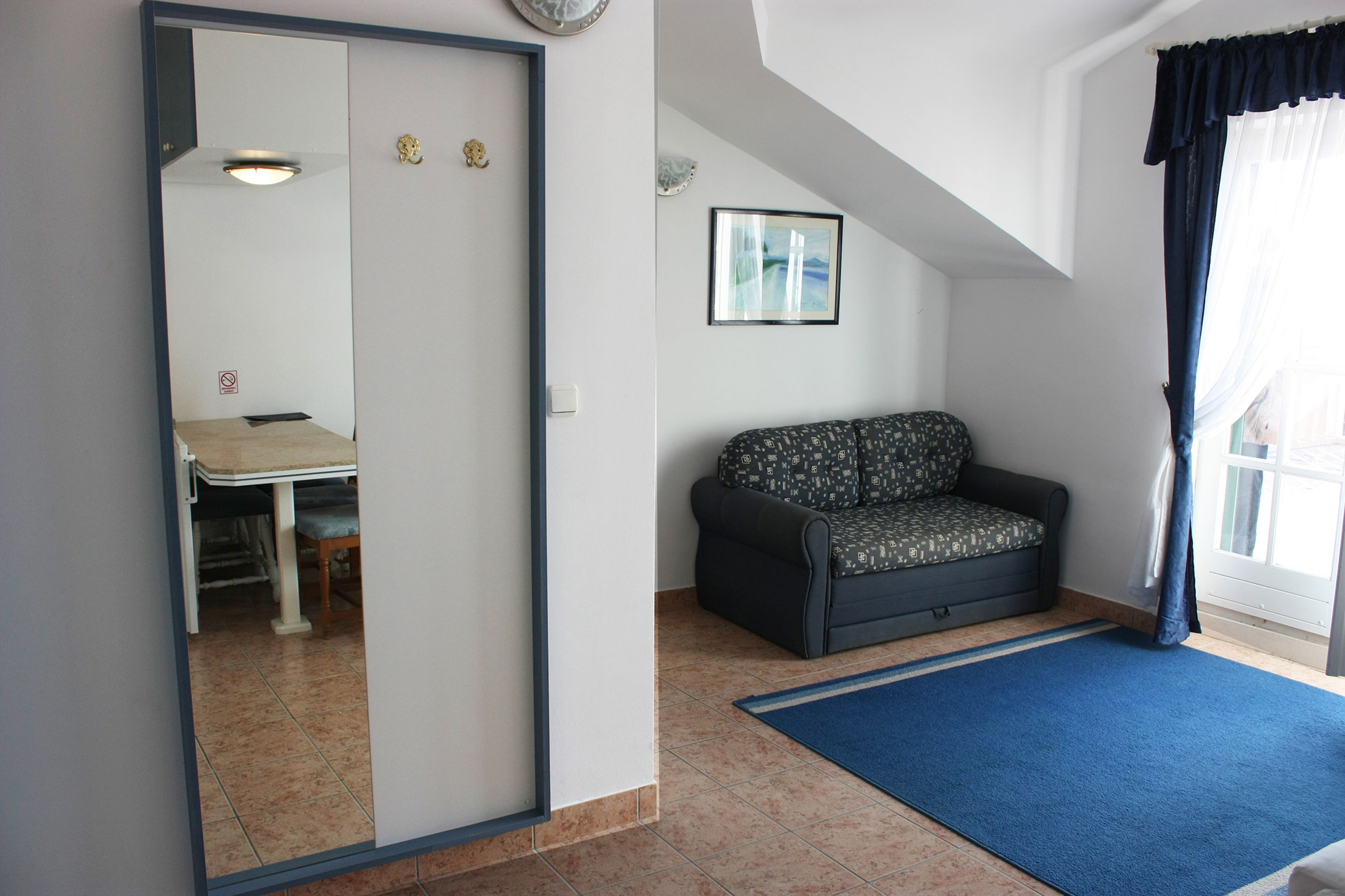 Une pièce avec un canapé, une table à manger et un tapis bleu.