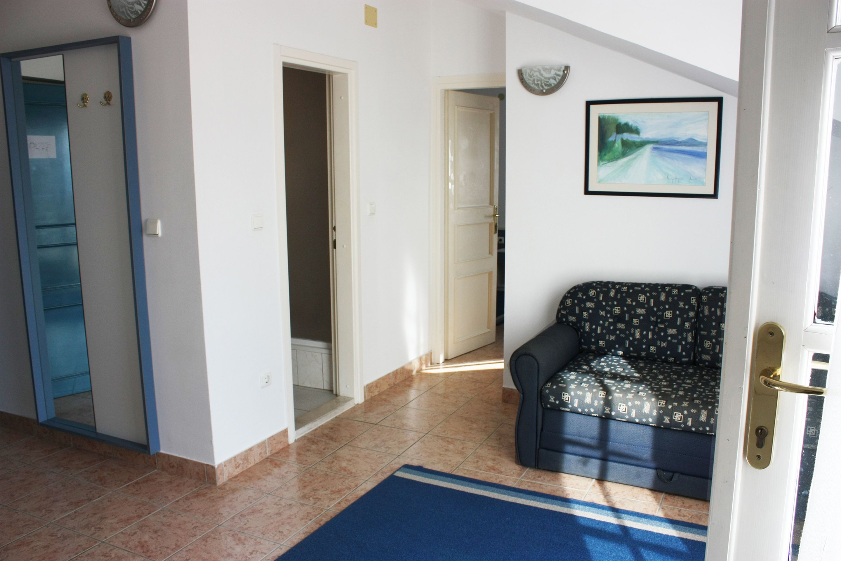 Un salon avec un canapé, une porte et un couloir menant à une autre pièce.