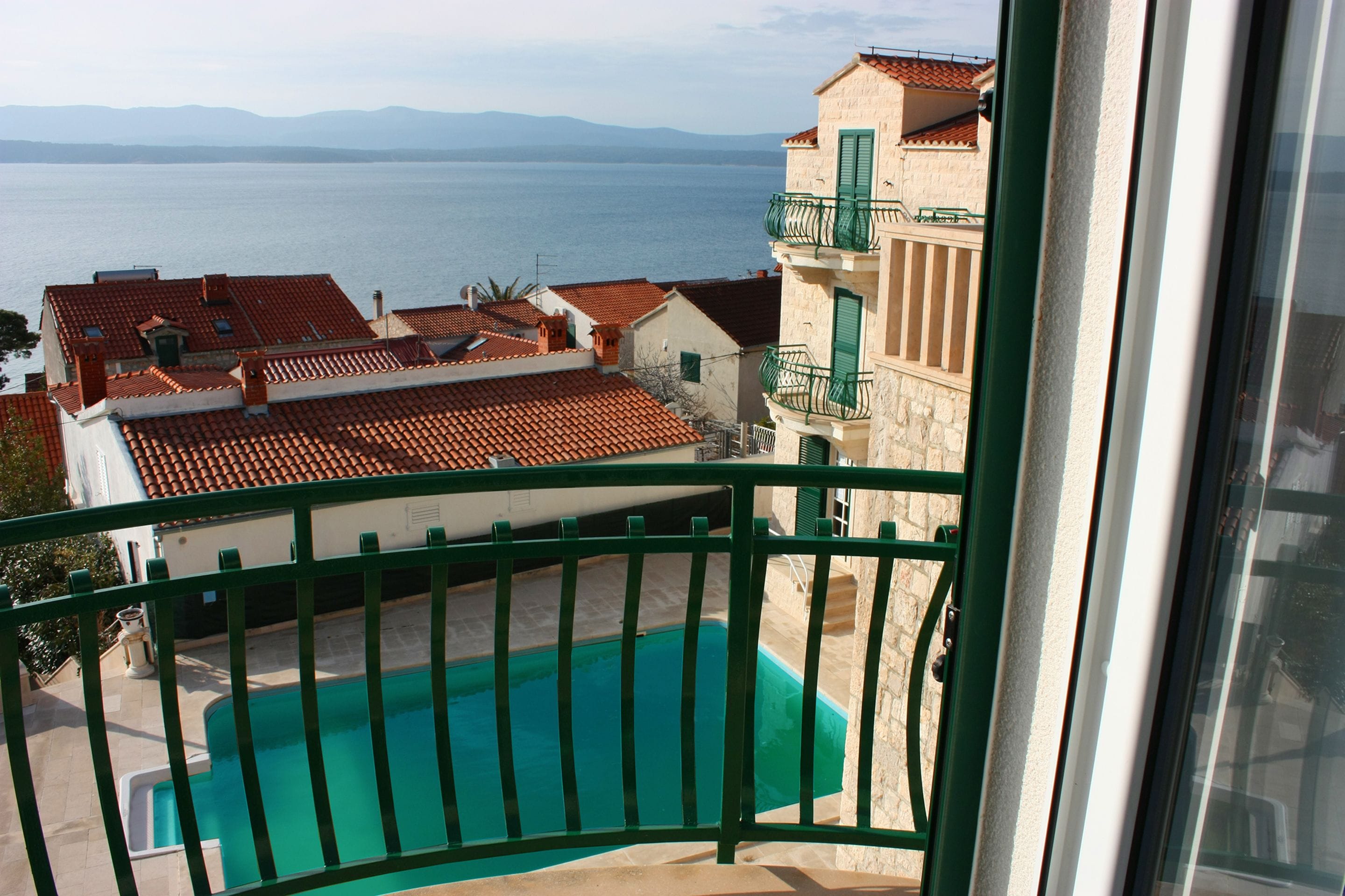 A balcony with a view of a swimming pool and the sea.