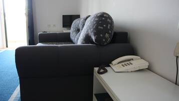 A hotel room with a bed, a bedside table with a telephone, and a television on the wall.