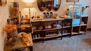 Una habitación con montaje tipo buffet, que incluye diversos alimentos, una estación de café y un refrigerador.